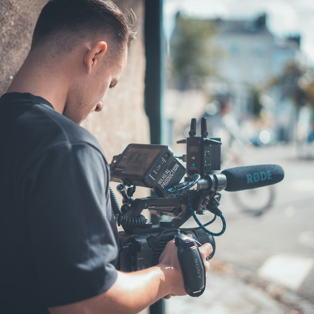 Ein professioneller Videograf filmt mit einer hochwertigen Kinokamera und Røde-Mikrofon direkt vor Ort im Betrieb. Ein professioneller Videograf filmt mit einer hochwertigen Kinokamera und Røde-Mikrofon direkt vor Ort im Betrieb.